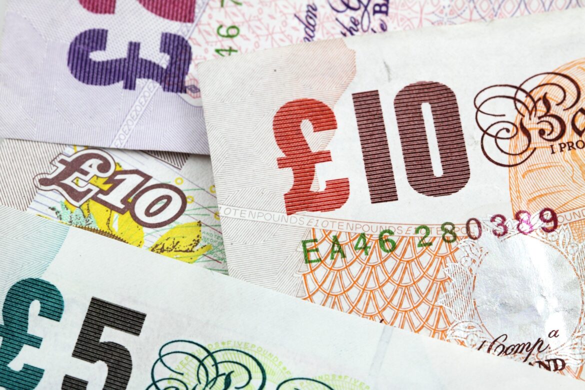 Close-up of overlapping euro banknotes, showing a red 100€ note and other denominations with intricate patterns.