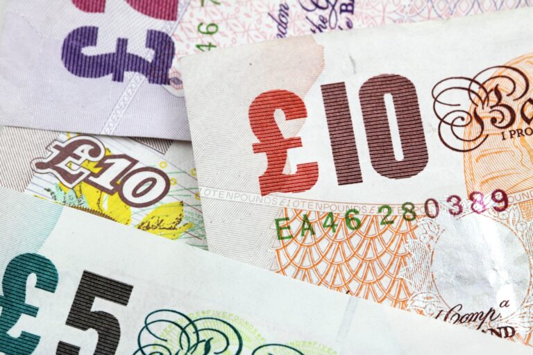 Close-up of overlapping euro banknotes, showing a red 100€ note and other denominations with intricate patterns.