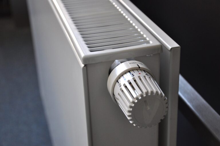 Close-up of a white radiator thermostat knob on a gray radiator, with a numbered dial (1–4).