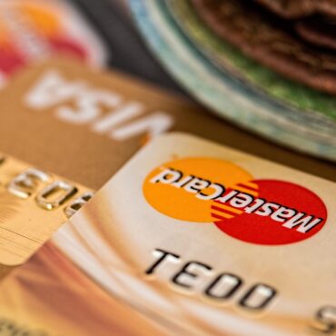 Close-up of a Mastercard credit card on a brown surface with the Mastercard logo visible, though slightly blurred.