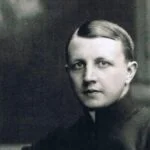 Black-and-white portrait of a person with slicked-back hair, wearing a high-collar dark garment and looking at the camera.