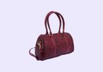 Burgundy leather handbag with double handles on a light purple background.