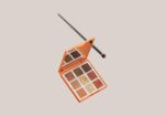 Orange makeup palette open to reveal twelve neutral/shimmers shades, accompanied by a makeup brush resting diagonally across the top.