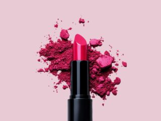 cosm - NOTE.radio - Polskie radio w UK | Polskie radio w Londynie Pink lipstick in a black case with crushed powder splattered behind it on a soft pink background, suggesting bold color makeup.